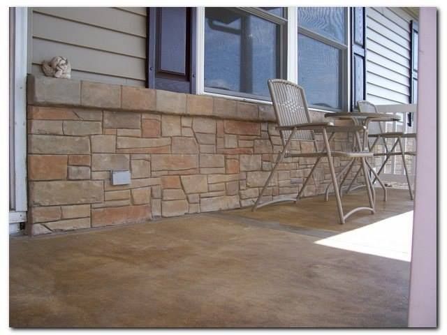 A porch with stone veneer, a table, and chairs sits beneath a window. The floor is a brown finish.