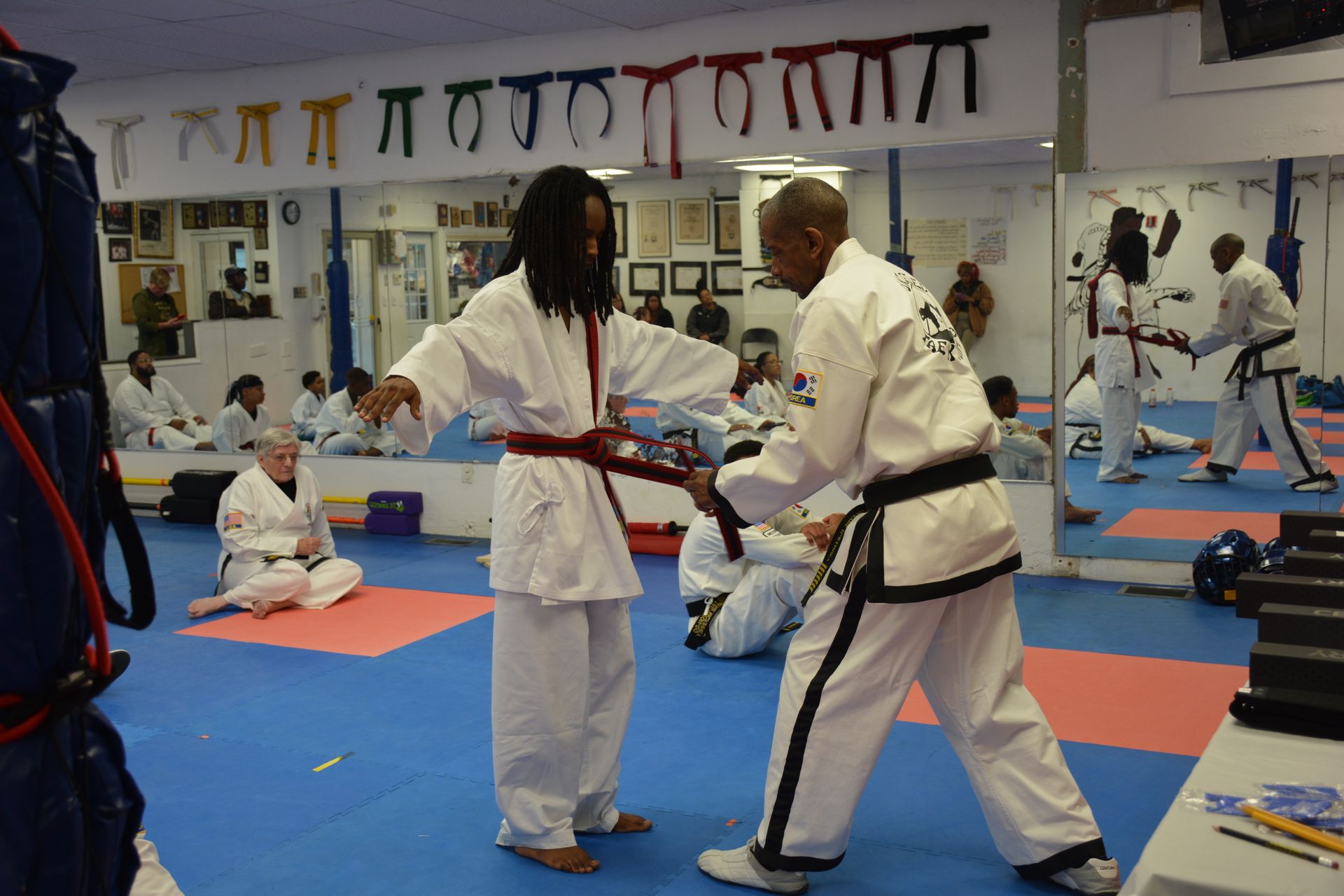 Martial arts class with two people practicing sparring in a dojo on blue mats