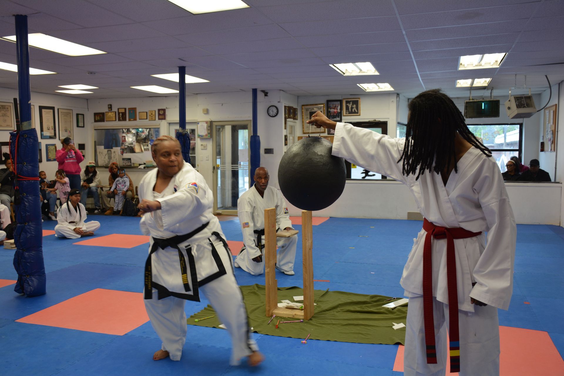 Martial arts class with two students in white uniforms practicing kicks and punches indoors