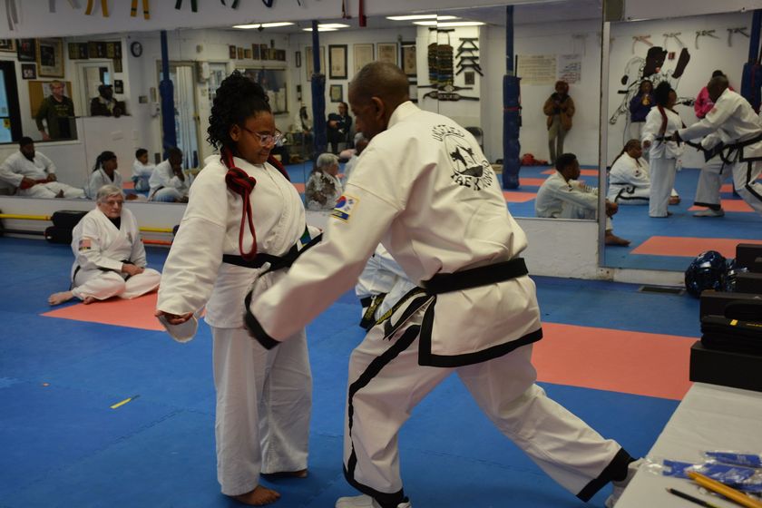 Martial arts class with two students practicing a kick in a mirrored dojo