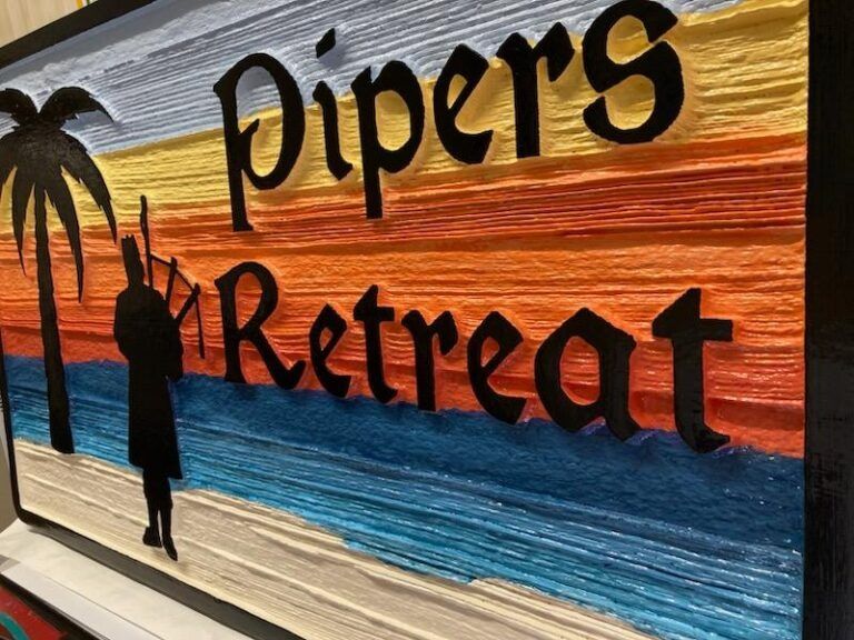 Sign reading “Pipers Retreat” over a sunset mural with an arched silhouette and a person on a dock