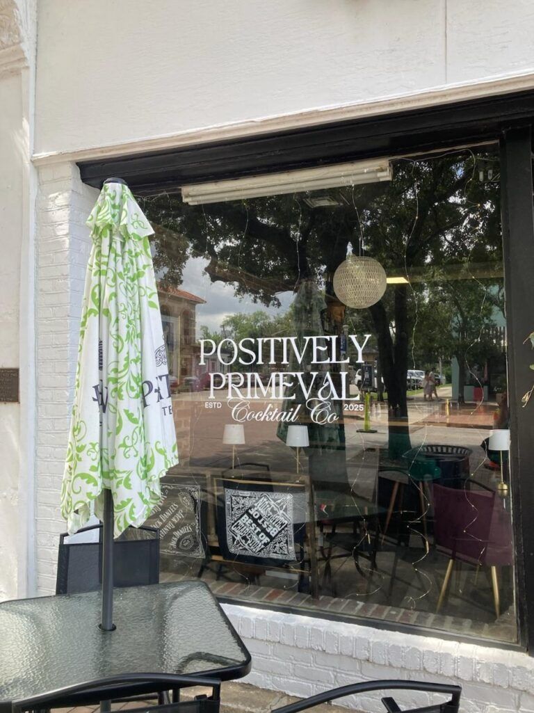 Storefront window with “POSTURE PREVAIL” lettering and a patio umbrella outside