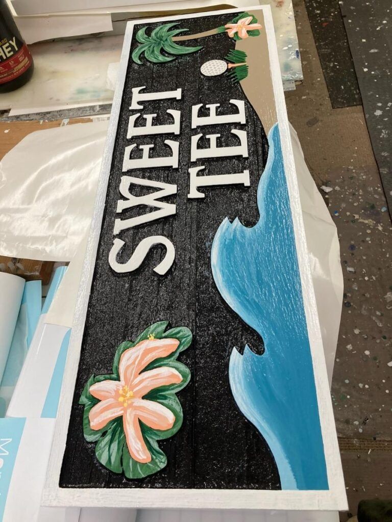“SWEET TEE” floral surfboard-shaped cake with blue water design and black background