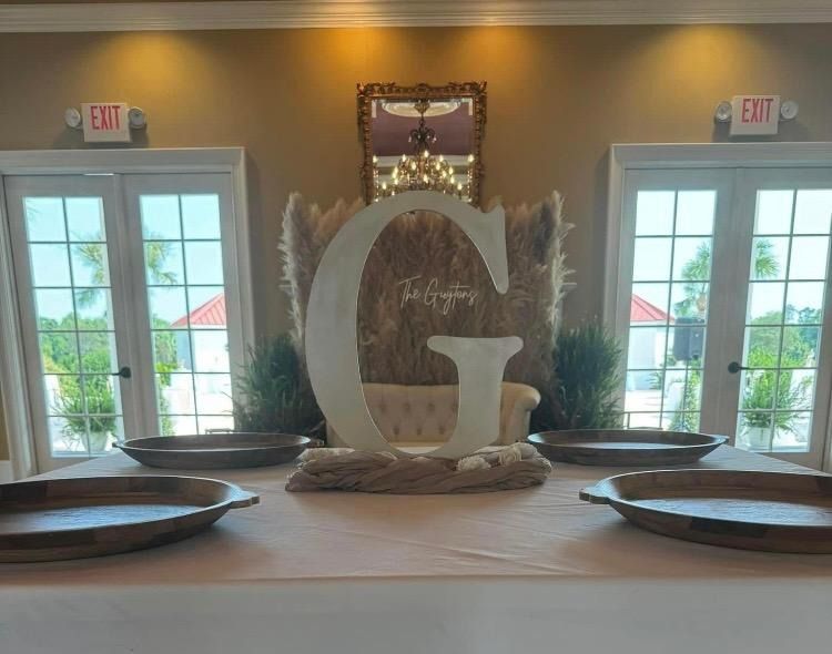 Decorated table with large white letter G centerpiece and plates, in a bright room with windows