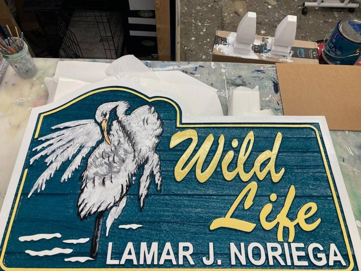 Blue-and-green sign with a white seagull and “Wild Life” above “Lamar J. Noriega”