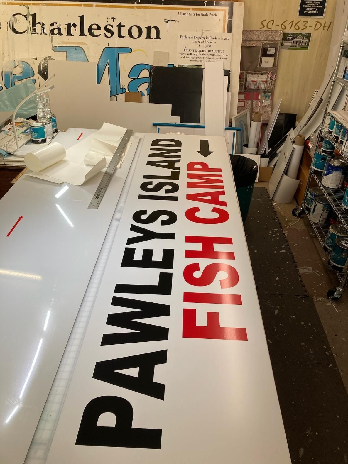 Promotional signs for Pawleys Island Fish Camp and Charleston displayed on a table in a shop
