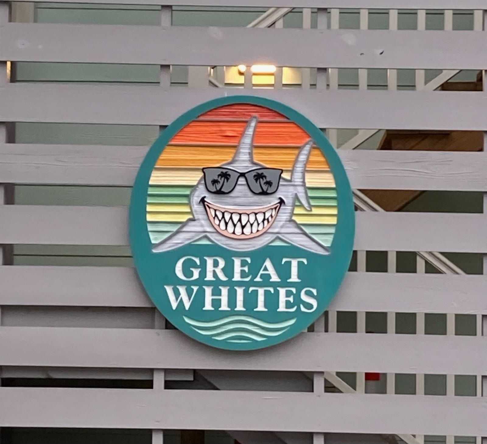 “Great Whites” shark logo on a turquoise sign attached to a gray fence