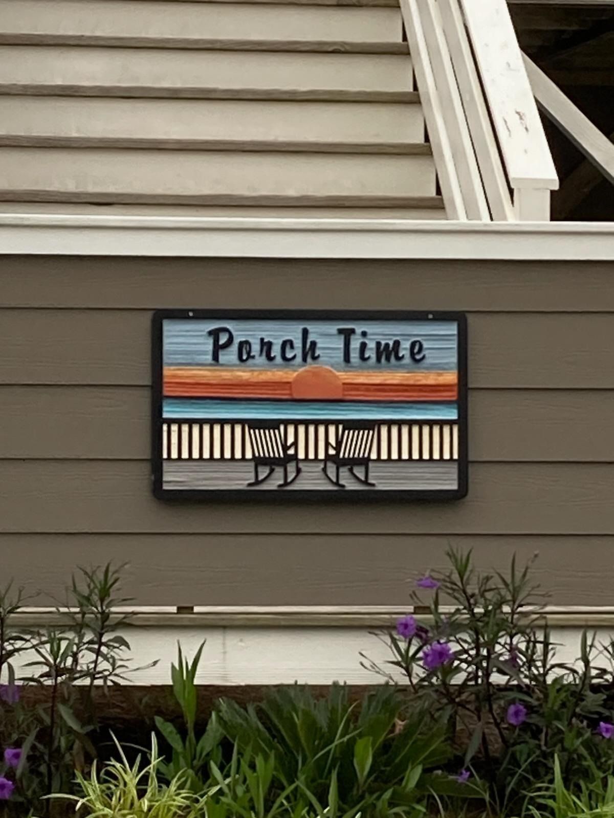 Porch sign reading “Porch Time” in front of beige siding and flowers