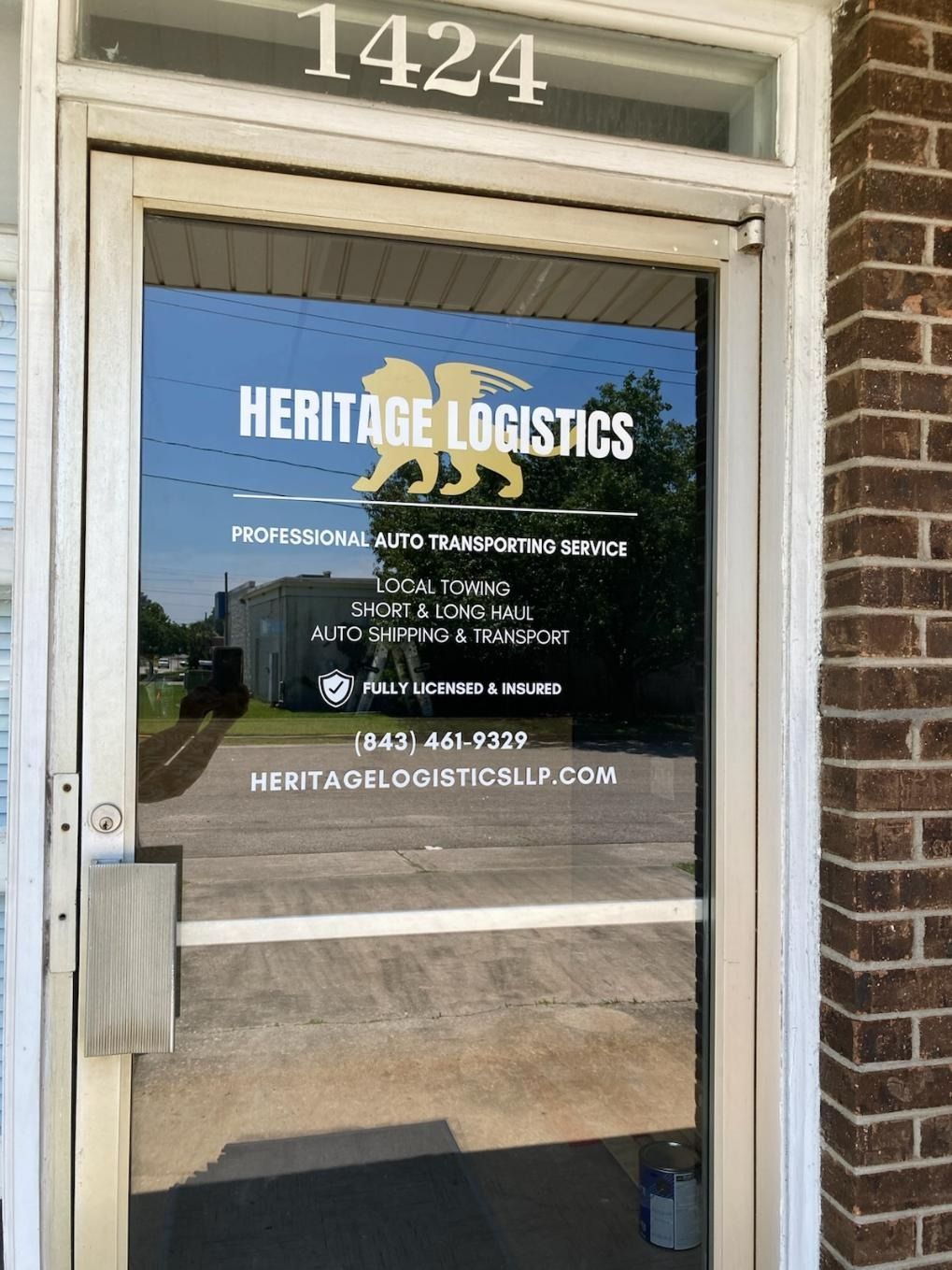 Heritage Logistics storefront door with blue window sign and address 1424
