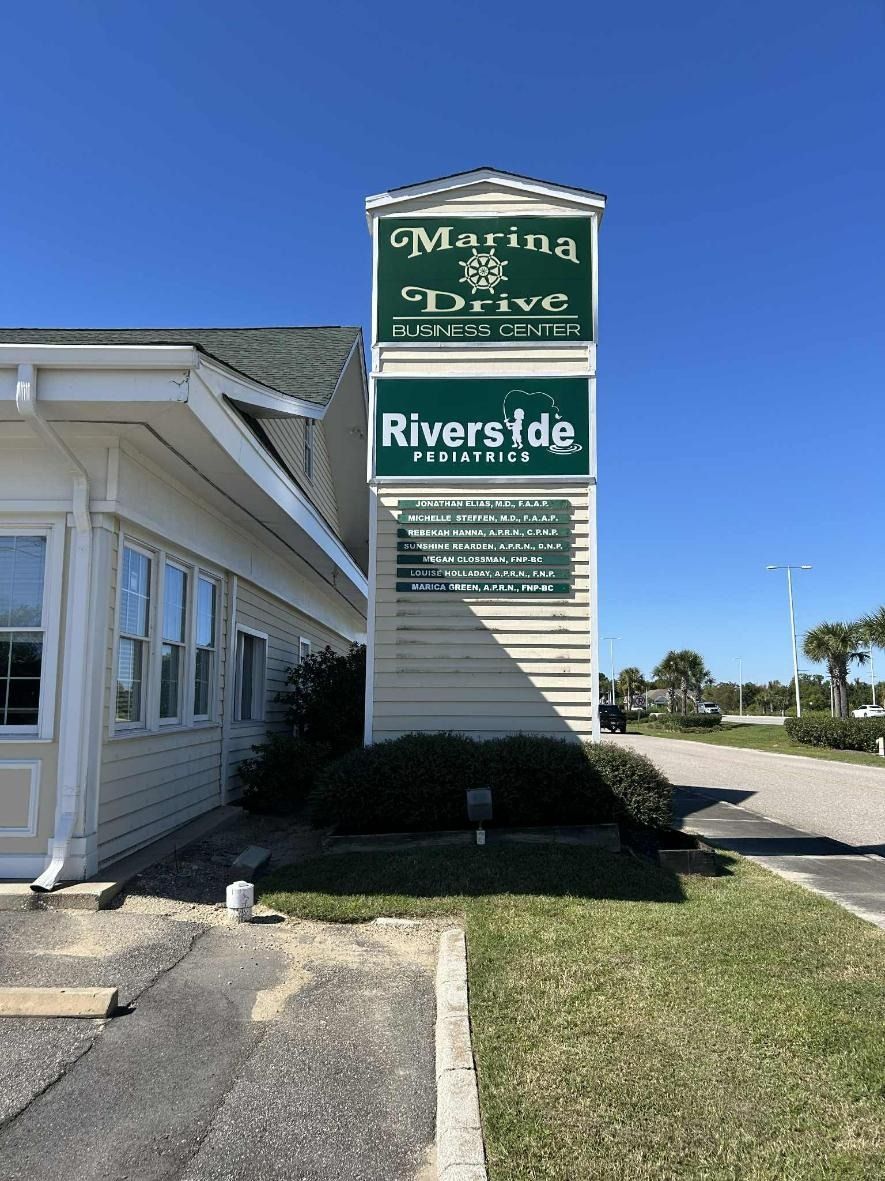 Entrance sign for Marina Prime and Riverside in a beige commercial building parking lot