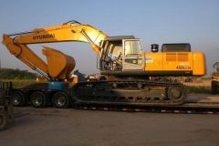 Yellow Hyundai excavator on a flatbed trailer, ready for transport.