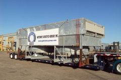 Large metal structure on a flatbed trailer for transport, with a logo on the side.
