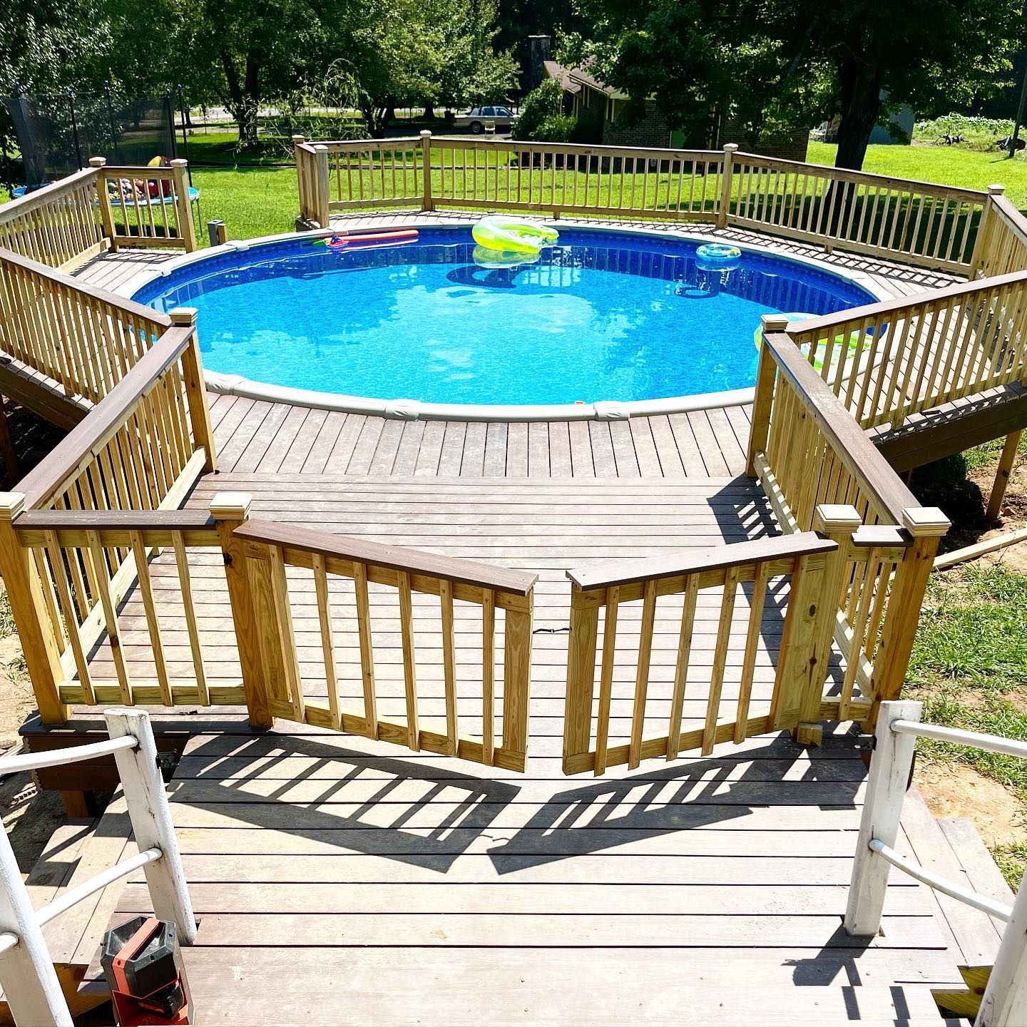 A large swimming pool is surrounded by a wooden deck.