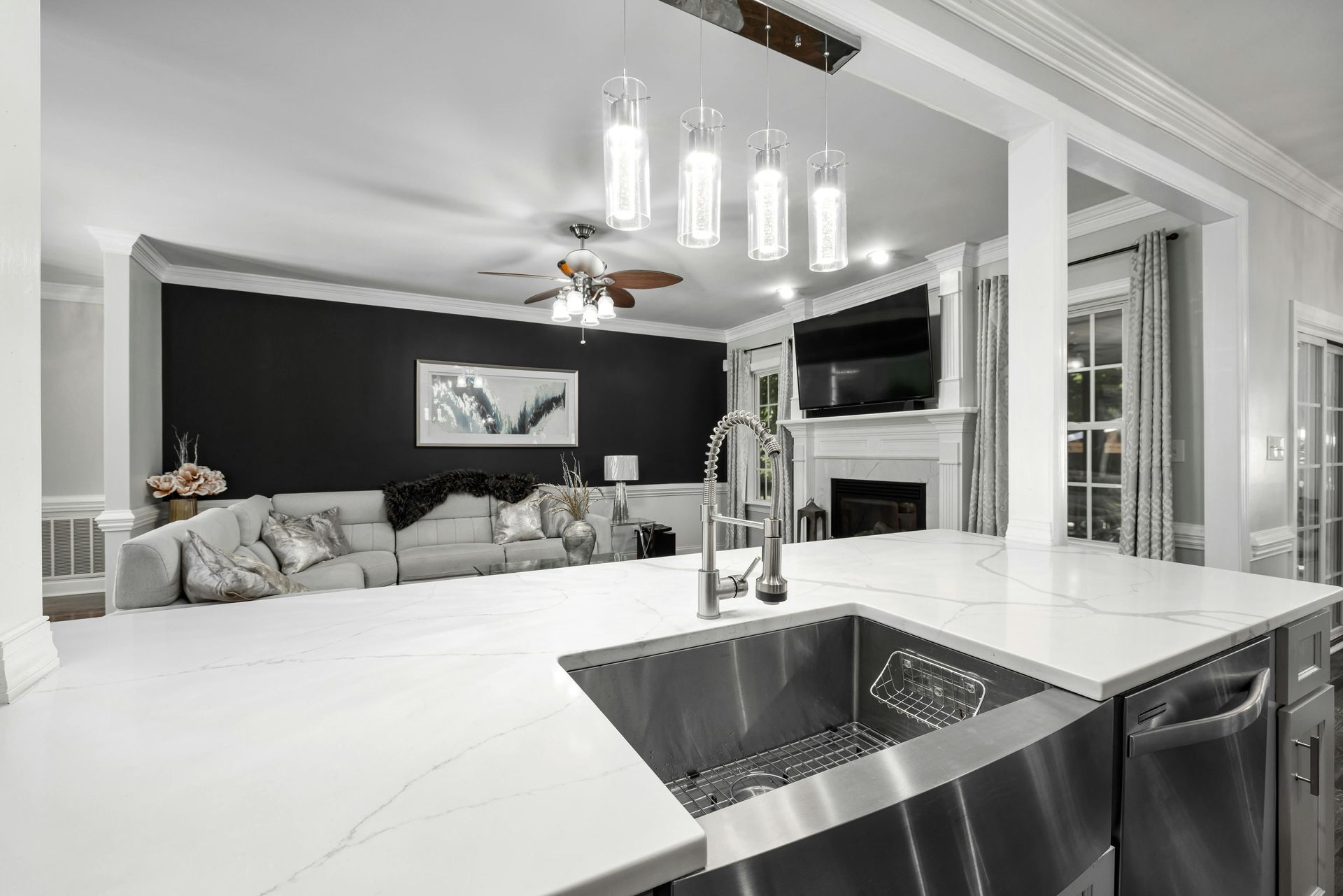 A kitchen with a stainless steel sink and a living room in the background.