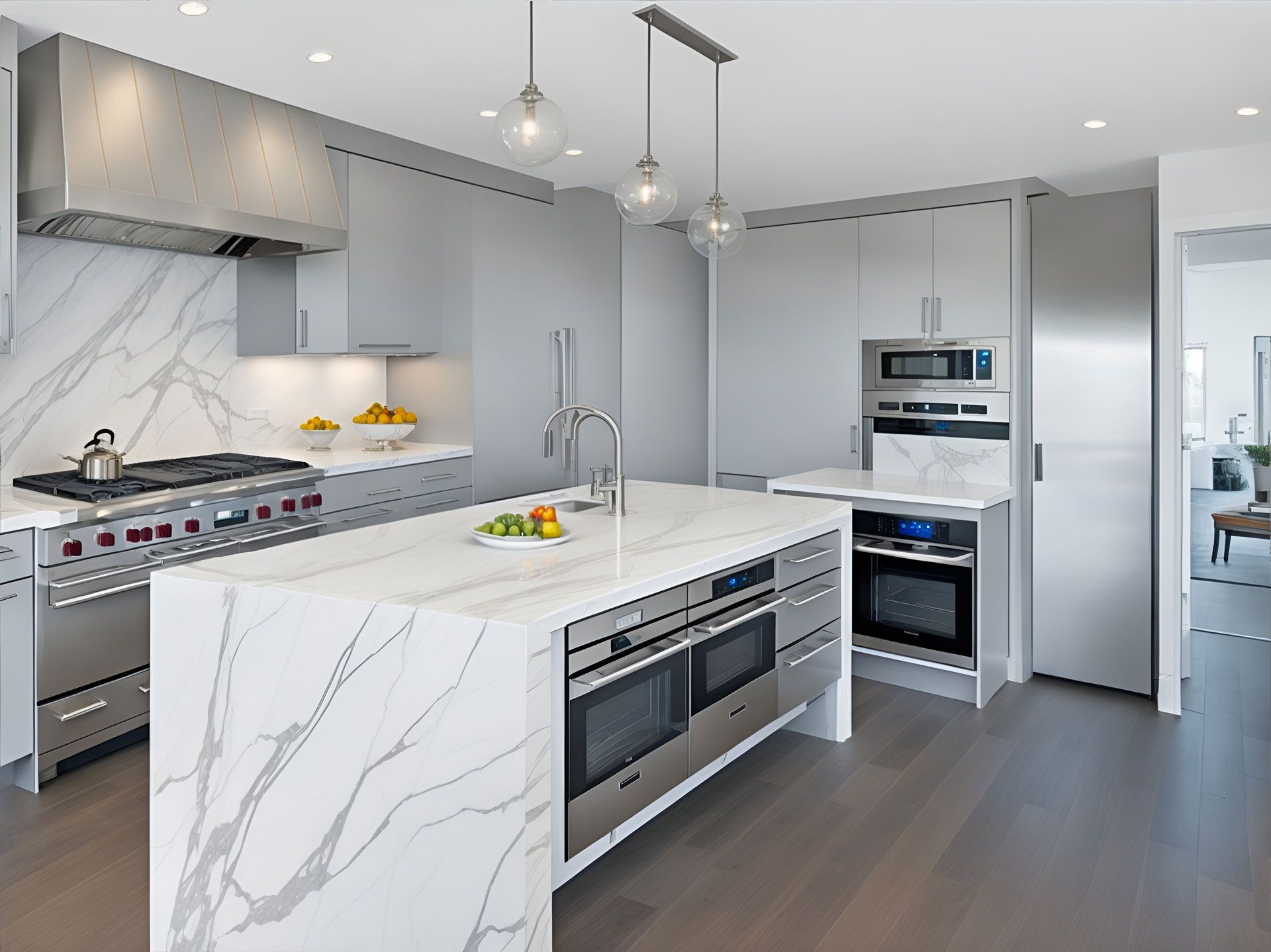 Modern kitchen with a white marble waterfall island, stainless steel appliances, gray cabinets, and hardwood floors.