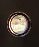 Vista circolare, attraverso uno spioncino scuro, di una luminosa scena esterna.