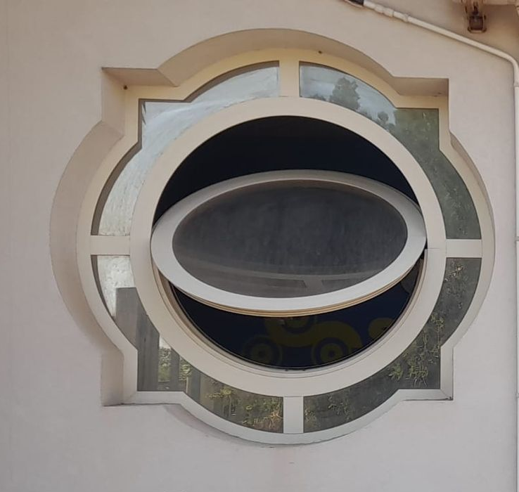 Finestra decorativa circolare con pannello ovale aperto in una parete in stucco beige