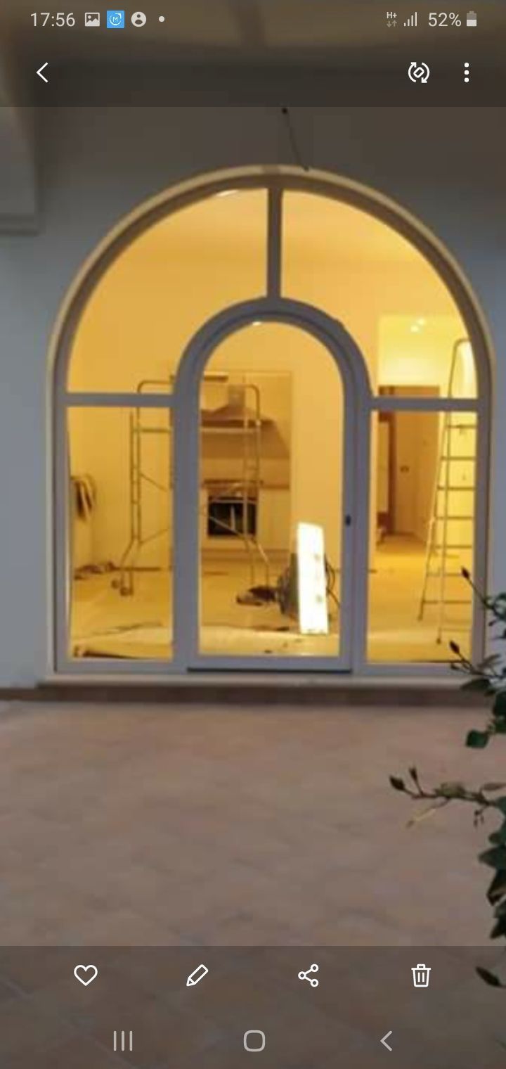 Porta ad arco in vetro illuminata di un edificio moderno di notte, con interni illuminati visibili dall'interno