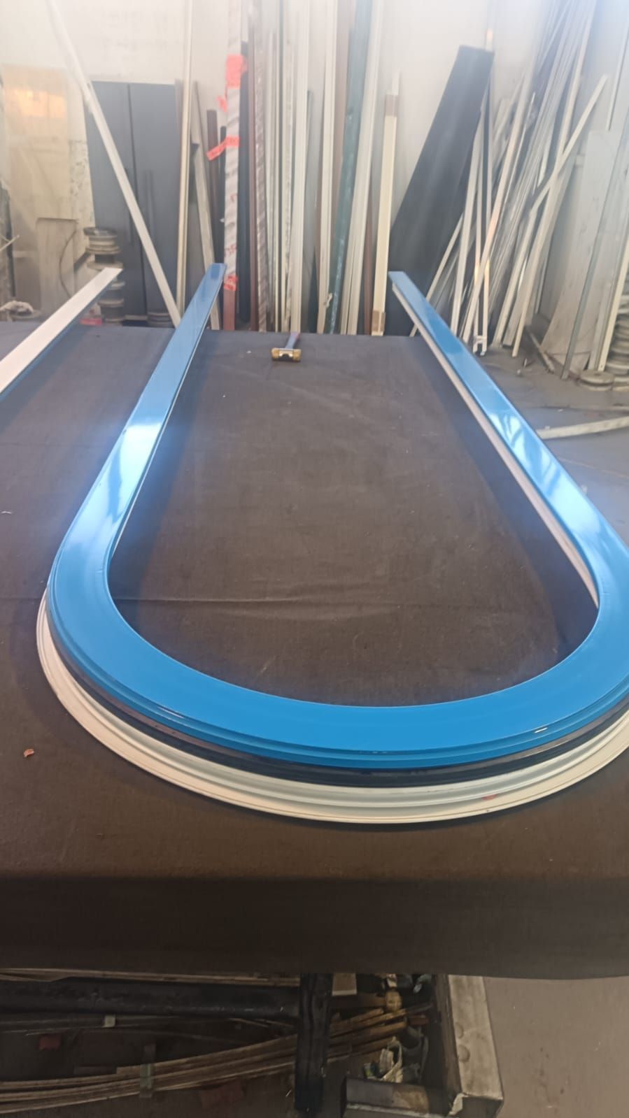 Nastro blu di un tapis roulant in una palestra, incorniciato da pali di supporto bianchi e attrezzature sullo sfondo.