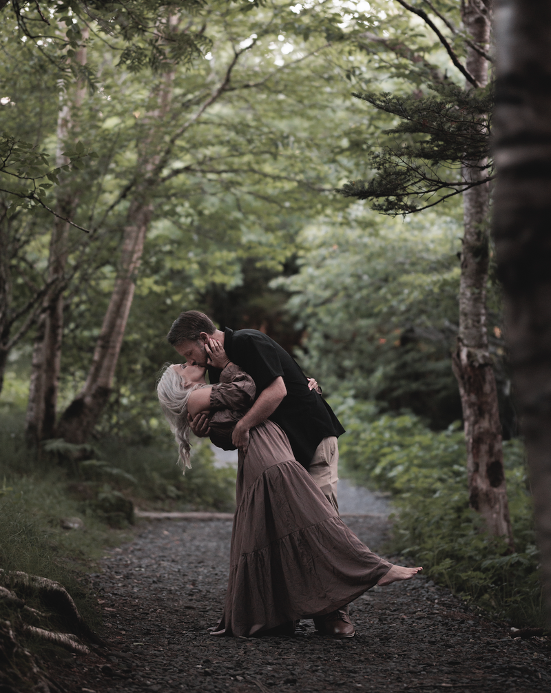 Brandon dipping Grace for a kiss on a wooded path