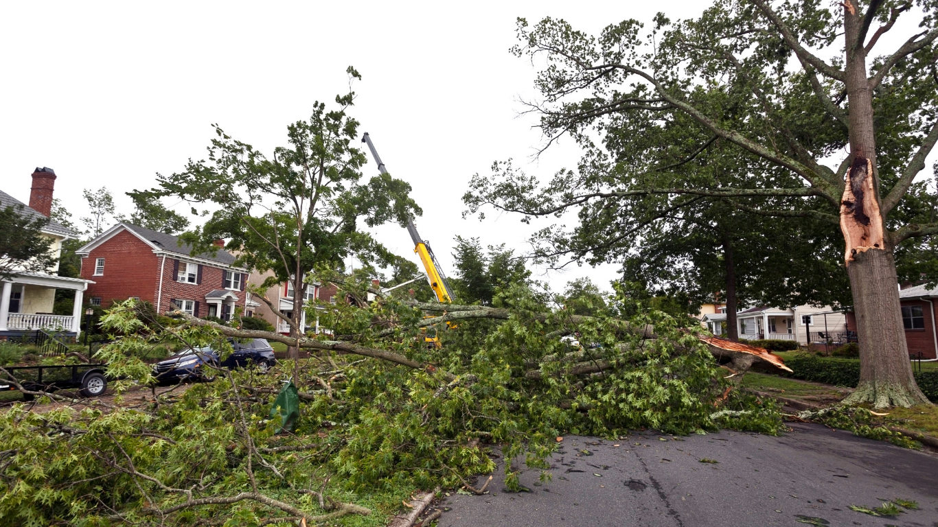 Storm-damaged neighborhood street with fallen trees, debris, and damaged houses after severe weather