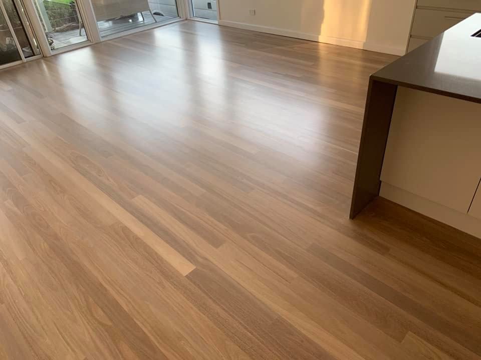 Light-colored hardwood flooring in a room with a kitchen island and sliding glass doors — Custom Floor Sanding In Somersby, NSW