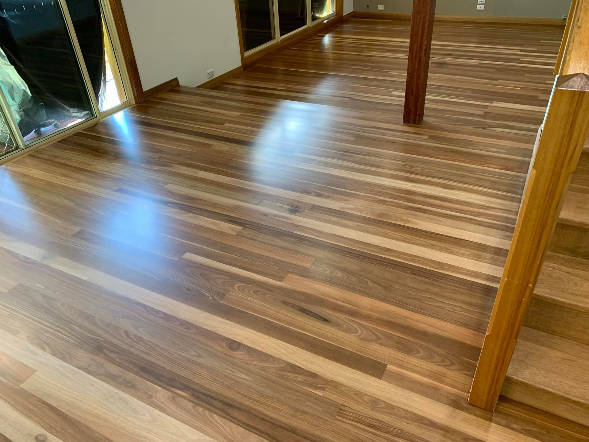 Wooden floor with a glossy finish, reflecting sunlight — Custom Floor Sanding In Somersby, NSW