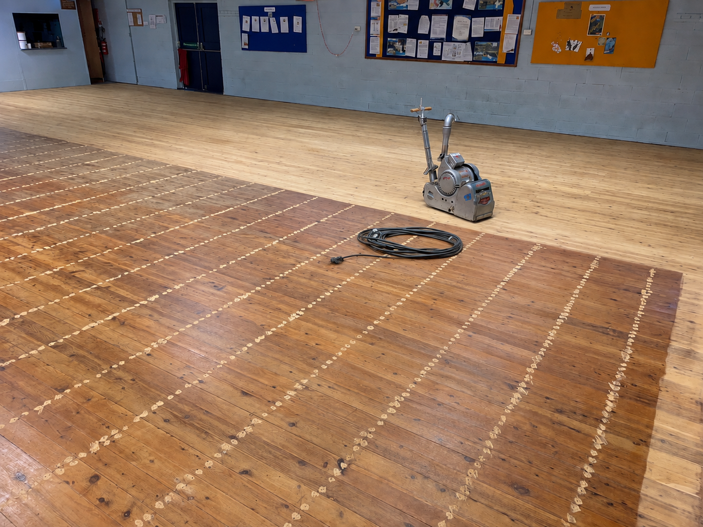 A large, outdoor wooden deck undergoing refinishing, with a sanding machine and power cord visible on the boards — Custom Floor Sanding In Somersby, NSW
