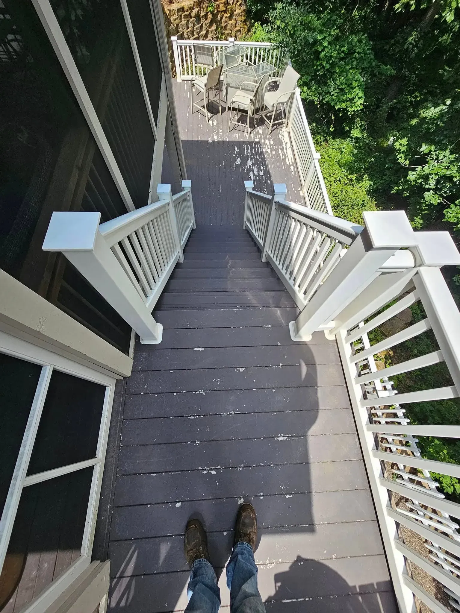 Overhead view of outdoor stairs leading to a deck with furniture. Person standing at top.