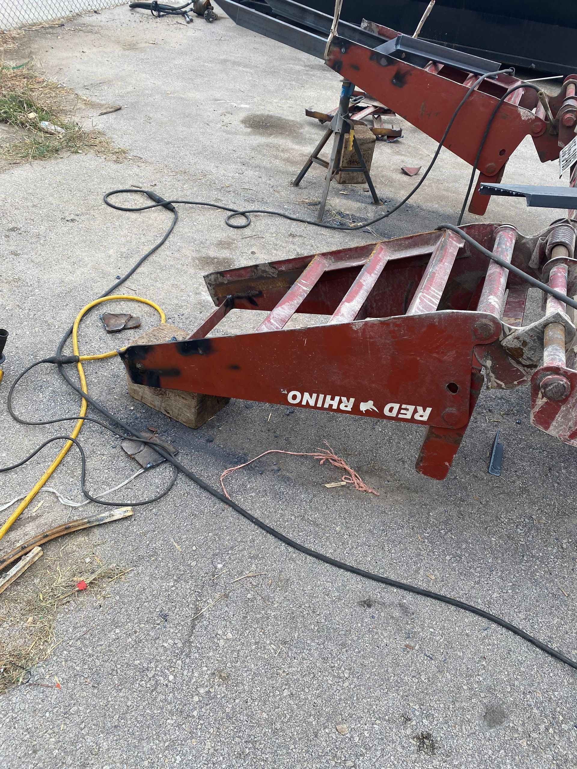 a red rhino trailer is sitting on the ground next to a boat .