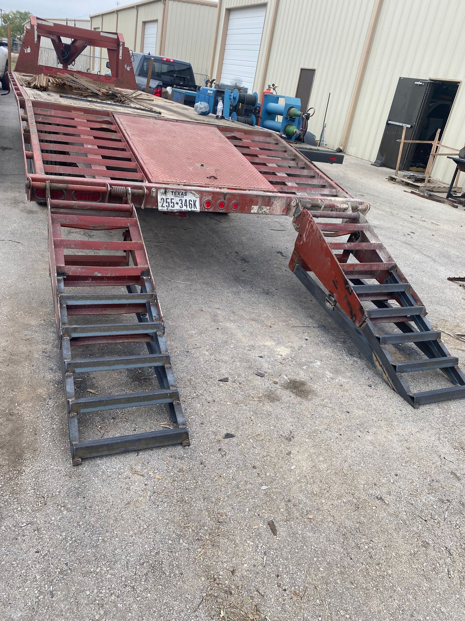 a trailer with ramps attached to it is parked in front of a building .