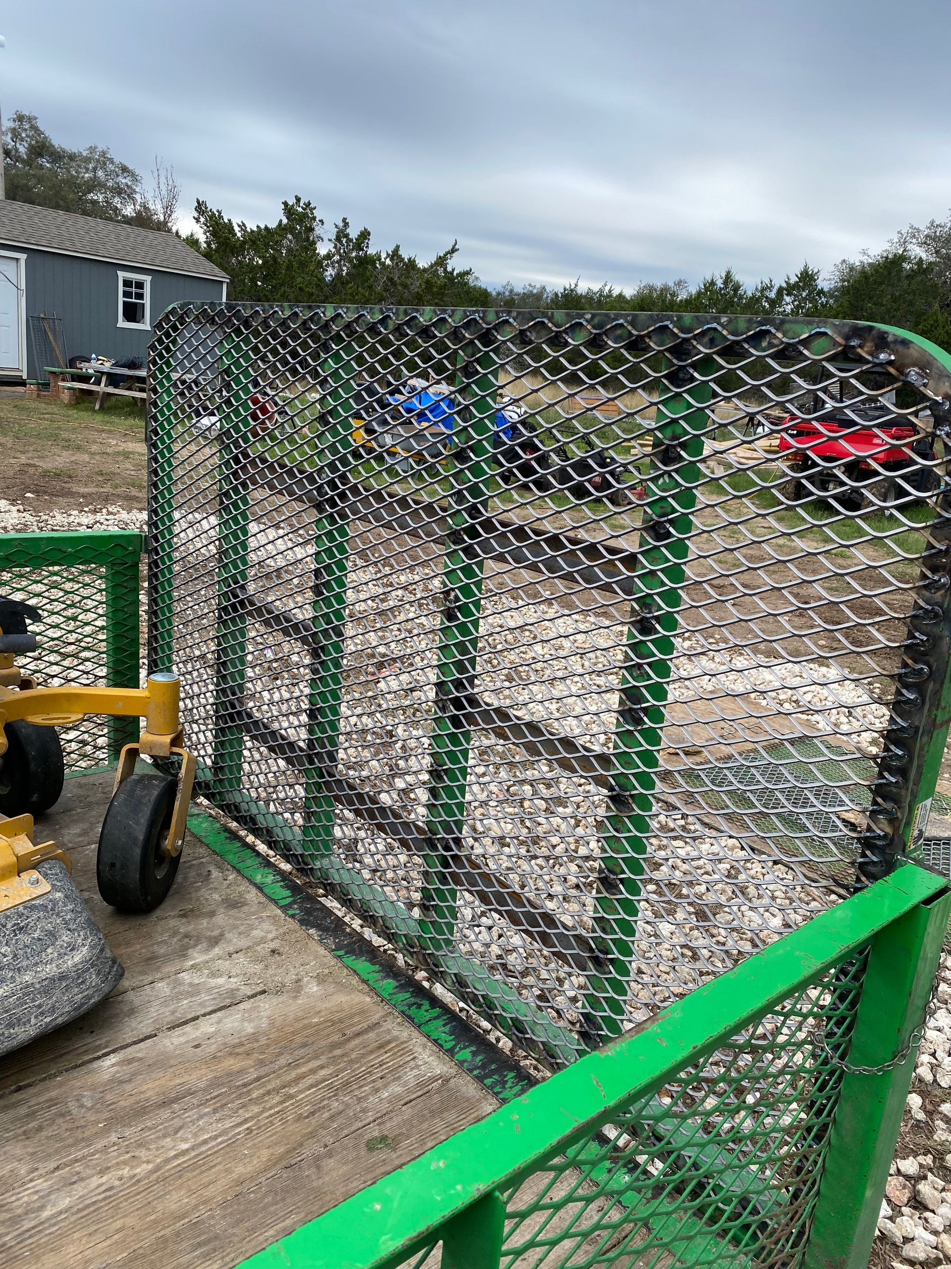 a green trailer with a chain link fence attached to it .