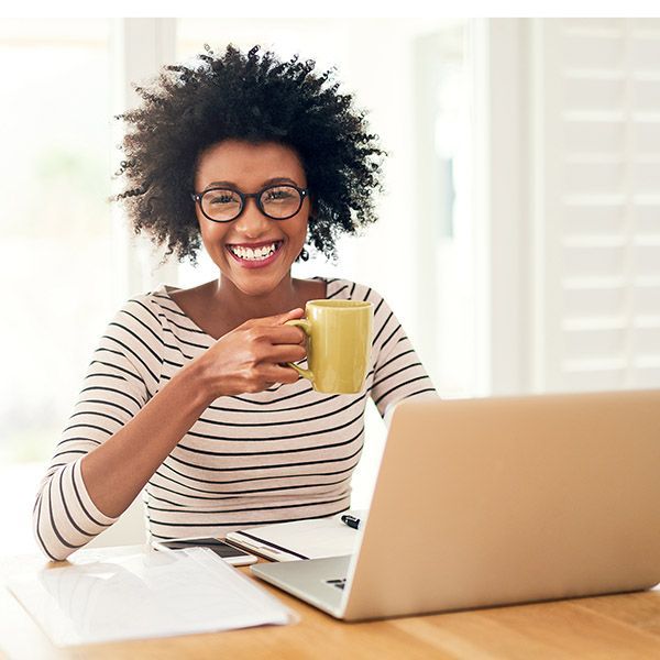 Young woman drinking coffee while working on her laptop at home