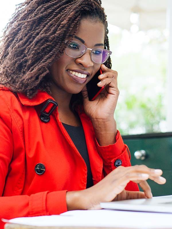 Cheerful woman using laptop and smartphone