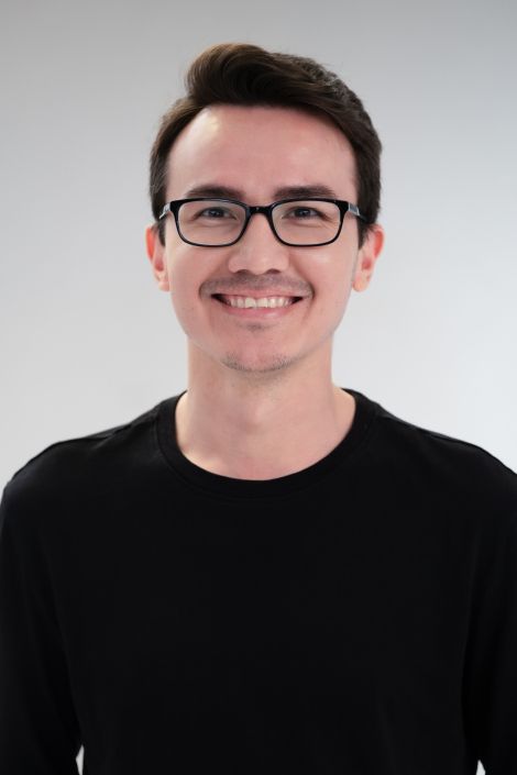 A man wearing glasses and a black shirt smiles for the camera