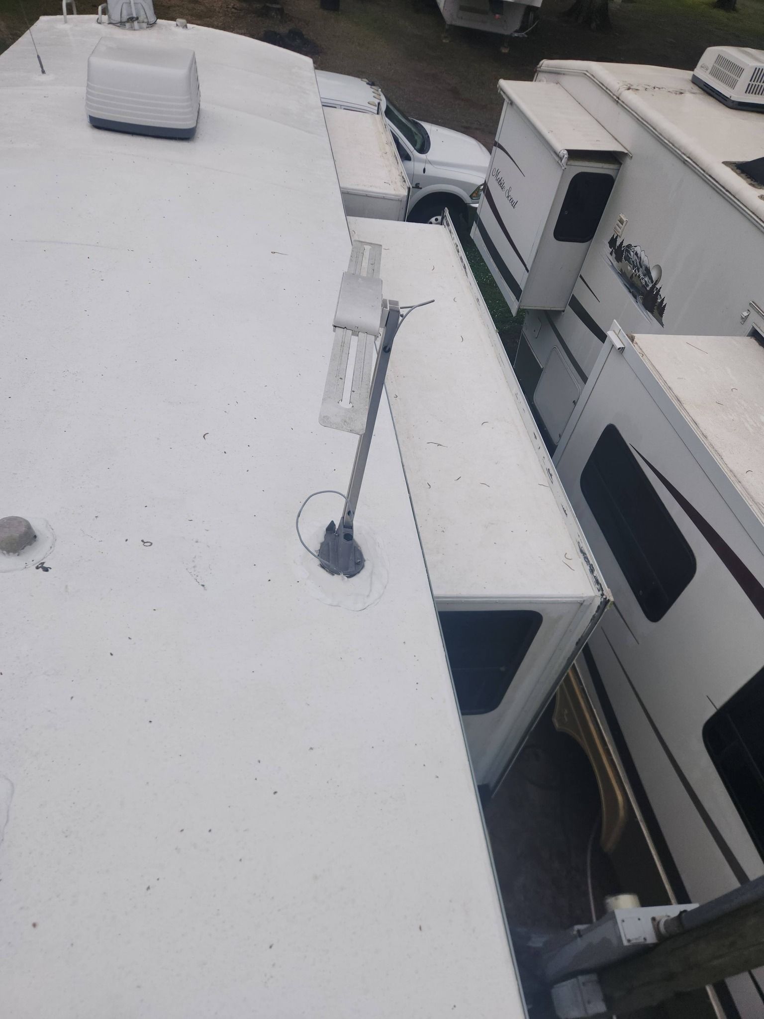 Snow-covered RVs parked closely together in a lot, viewed from above