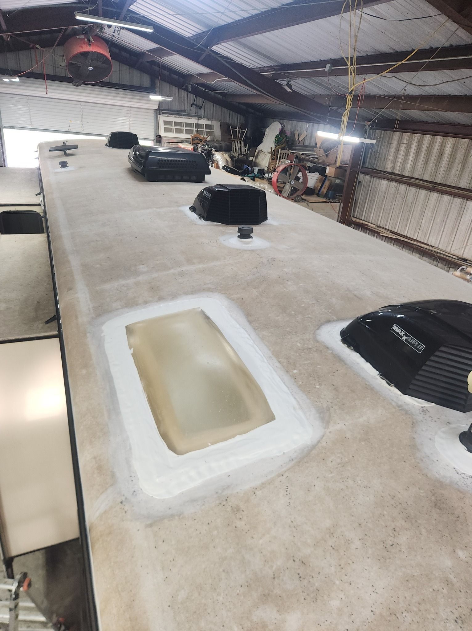 Covered industrial workspace with a long concrete table, black equipment bags, and corrugated metal roof above