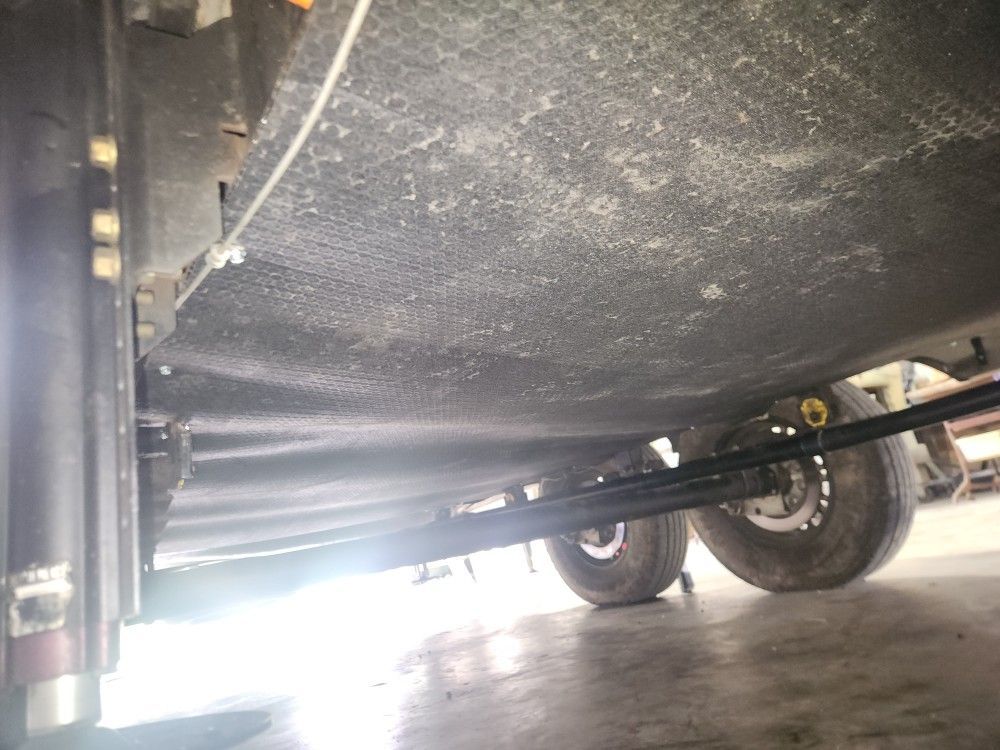 Underneath a vehicle, showing the undercarriage and wheels on a garage floor.