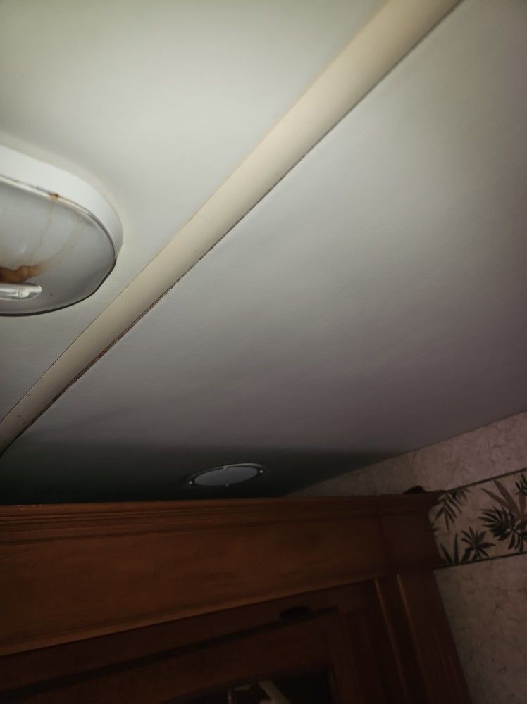 Ceiling with round light fixtures and a beige trim above a wooden cabinet