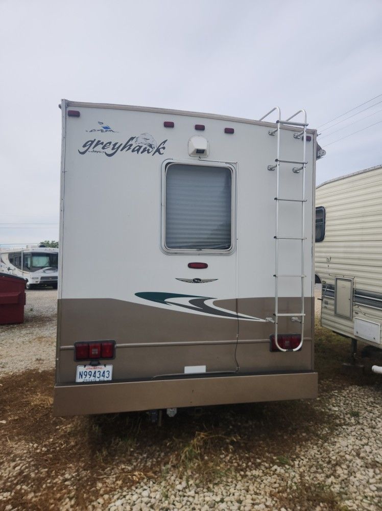Front view of a white Georgetown RV with tan lower trim parked on gravel in a lot