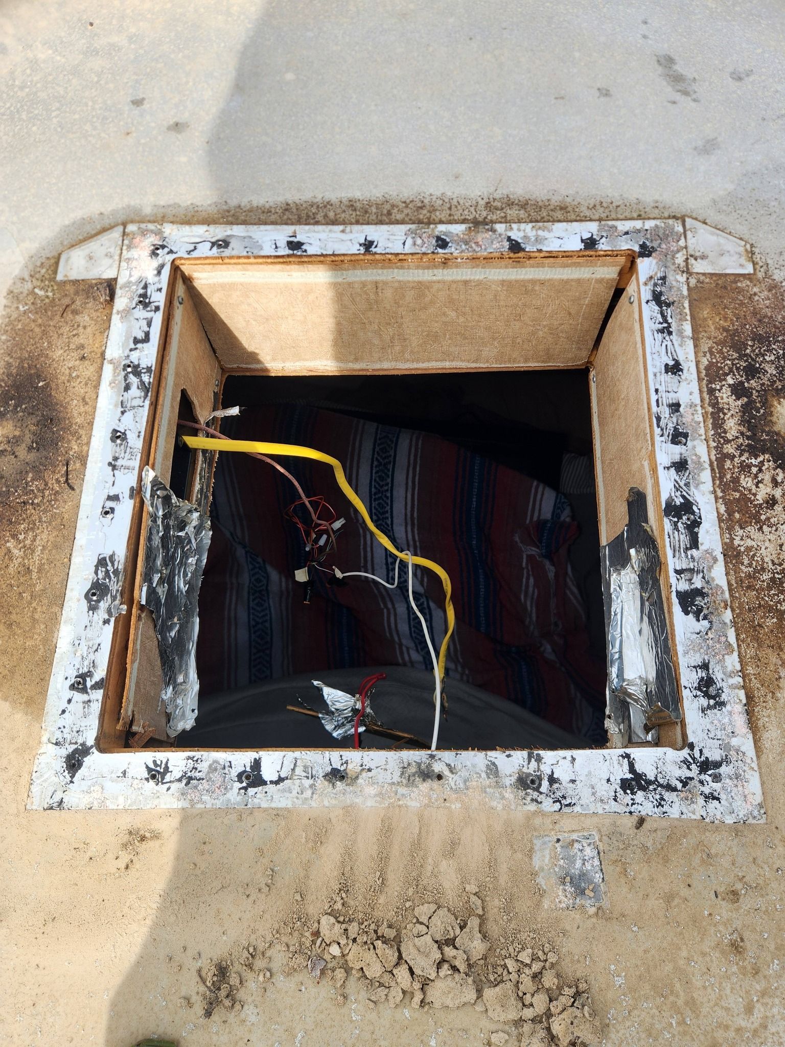 Open utility hatch with exposed wires in a concrete surface