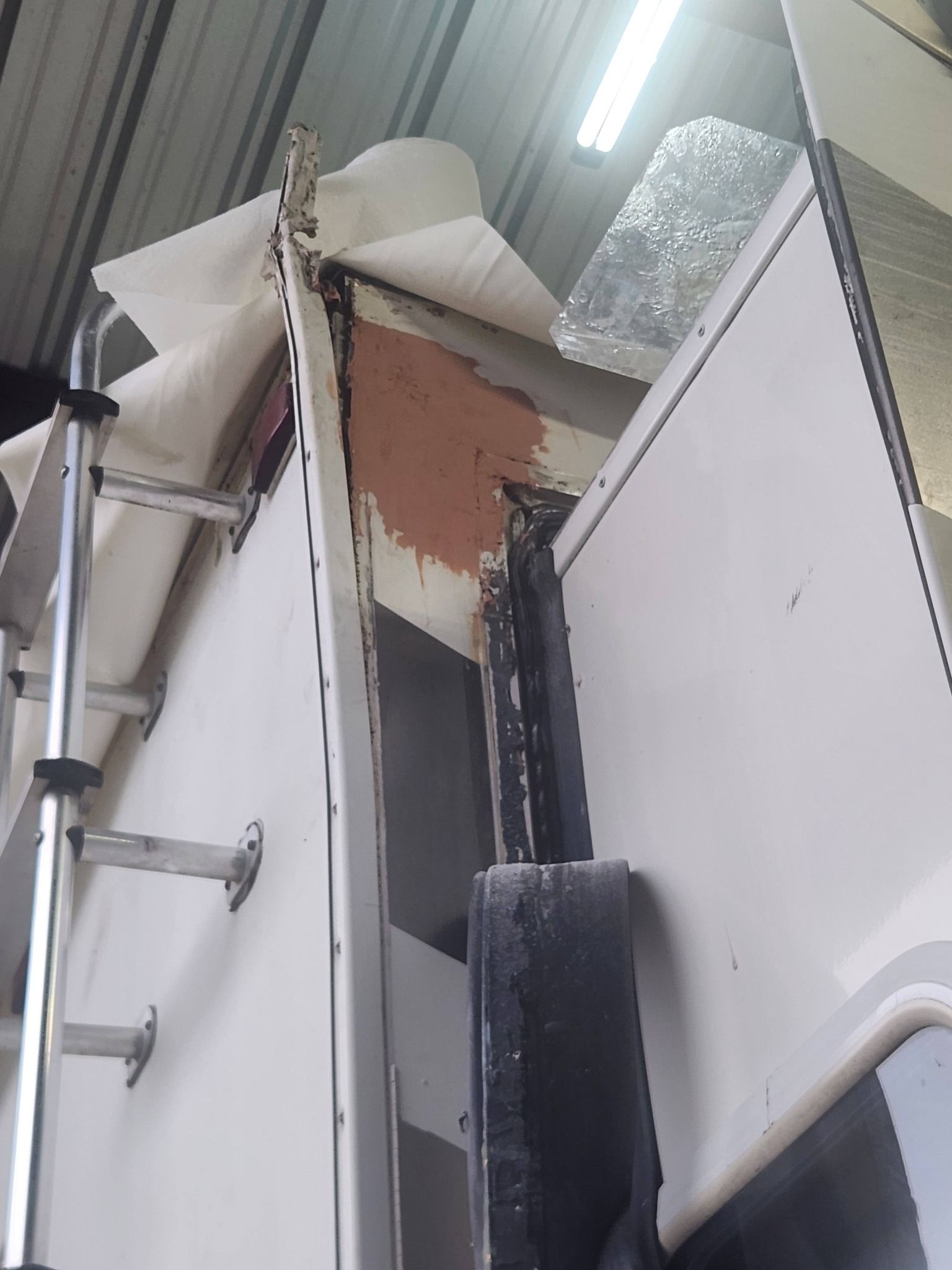 Damaged ceiling panel with exposed insulation and metal framing in a room or hallway