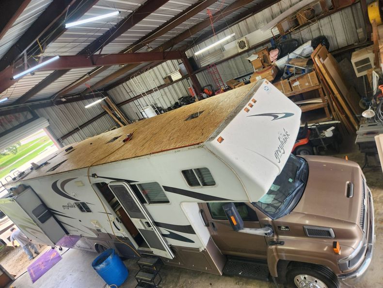 Camper trailer attached to a brown truck inside a cluttered metal shed