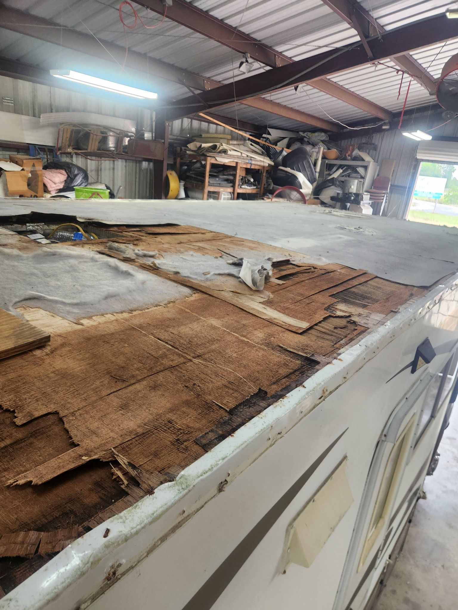 Damaged countertop in a cluttered workshop with peeling laminate and exposed particleboard.