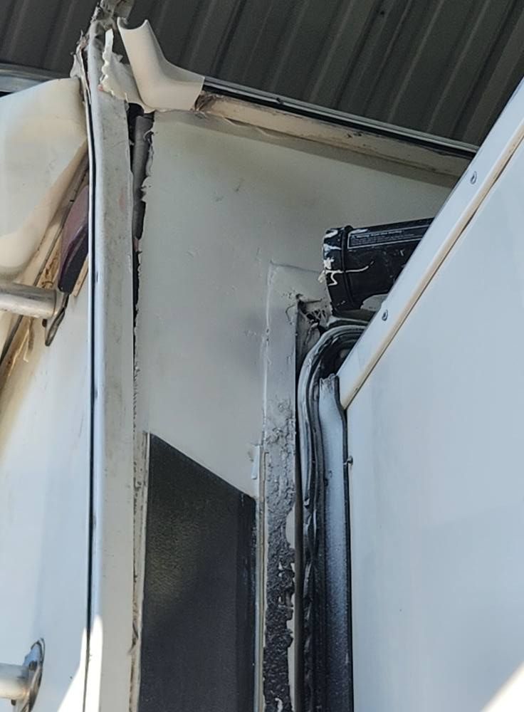 Damaged exterior wall and roof corner with black soot or charring around a vertical seam.
