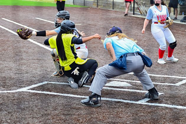 Baseball player sliding into home plate, catcher in front. Blue and gold uniforms, action shot.