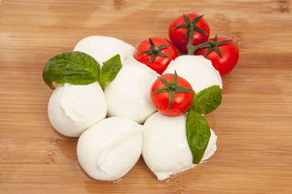 Una palla di mozzarella bianca su un piatto, tagliata a metà per mostrare il ripieno cremoso.