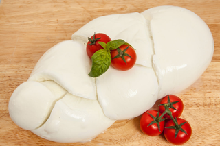 Pagnotta di formaggio bianco intrecciata su un tagliere di legno.