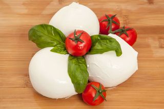 Burrata bianca su un piatto bianco, con superficie lucida e coperchio legato.