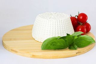 Una palla di mozzarella bianca su un piatto, tagliata a metà per mostrare il ripieno cremoso.